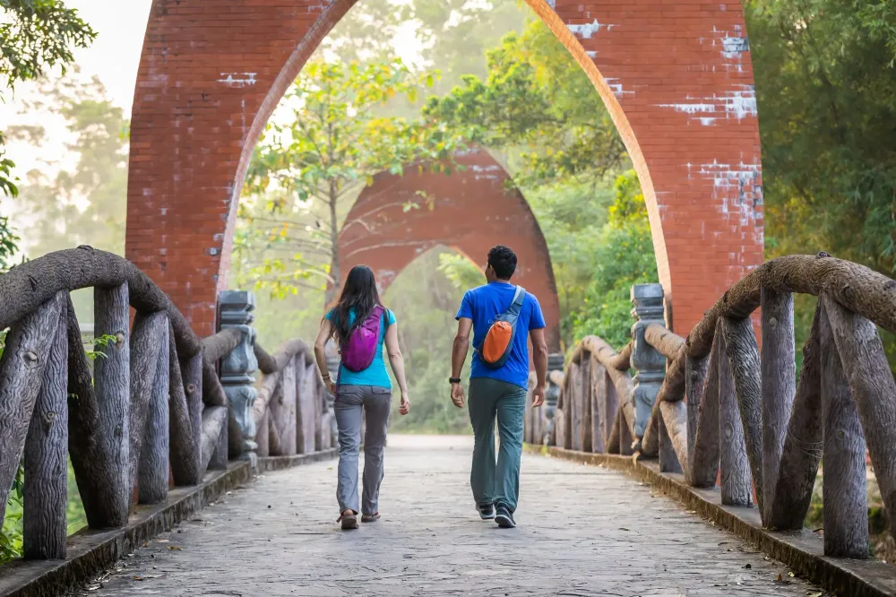 two people walking along bridge touring with small backpacks on